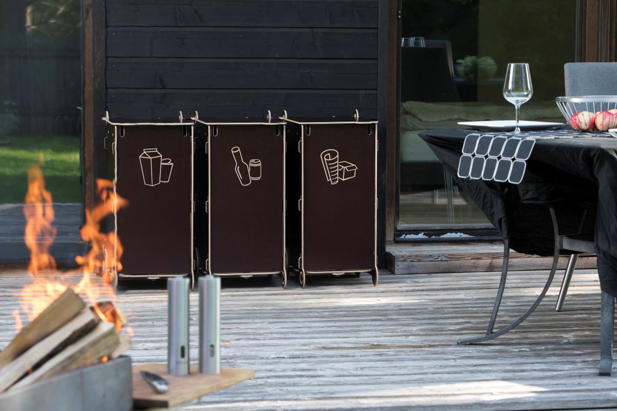 Eco-friendly outdoor waste sorting bins made from sustainable materials, placed on a wooden terrace near a home, symbolizing modern sustainable living.