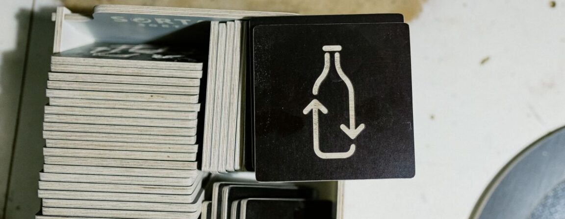 Close-up of durable plywood material used for manufacturing recycling bins, showing high-quality wooden layers and engraved waste sorting symbols.