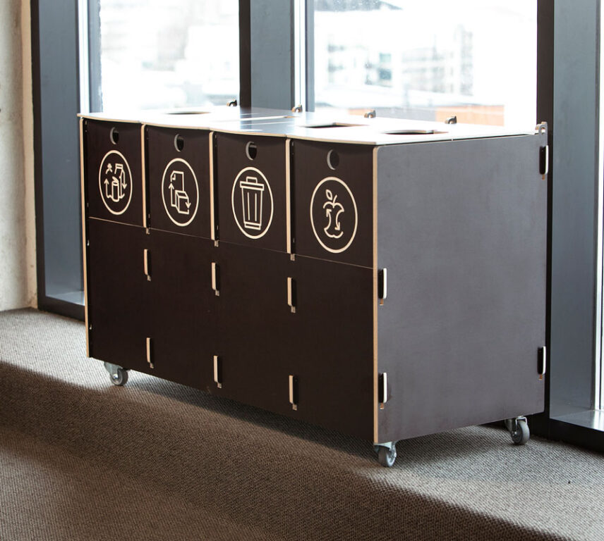 Recycling bins made of durable plywood with labeled sections for packaging, paper, mixed, and bio waste, placed in a modern office setting.