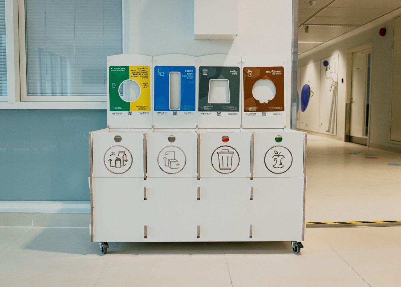 Recycling bins for hospitals with clear labels for glass, plastic, paper, waste, and bio waste.