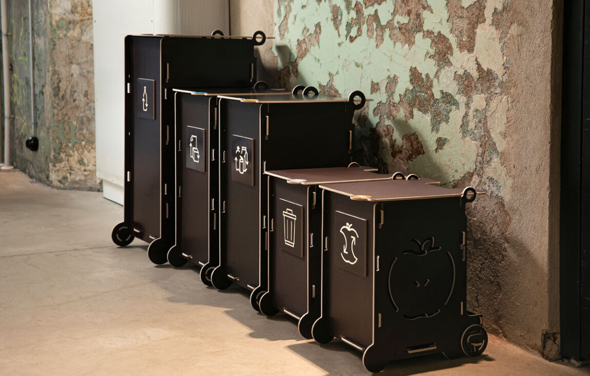 Black office waste bins with lids and recycling symbols, featuring separate sections for paper, packaging, mixed, and bio waste.