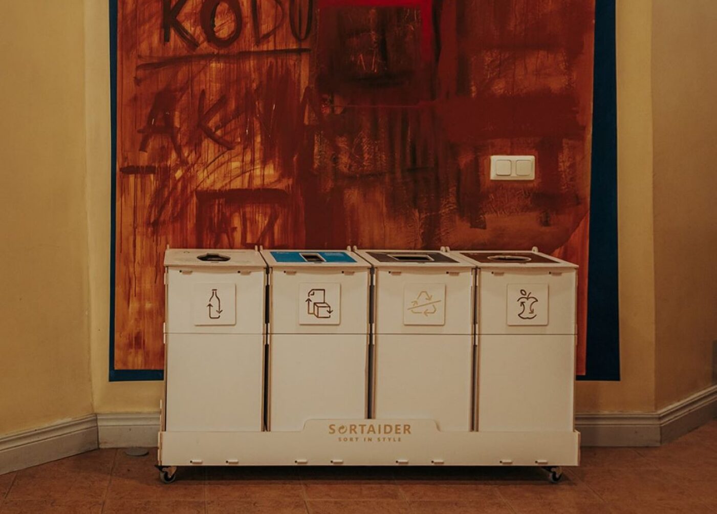 Recycling bins with lids in a shared indoor space to reduce odours and keep sorting areas tidy.