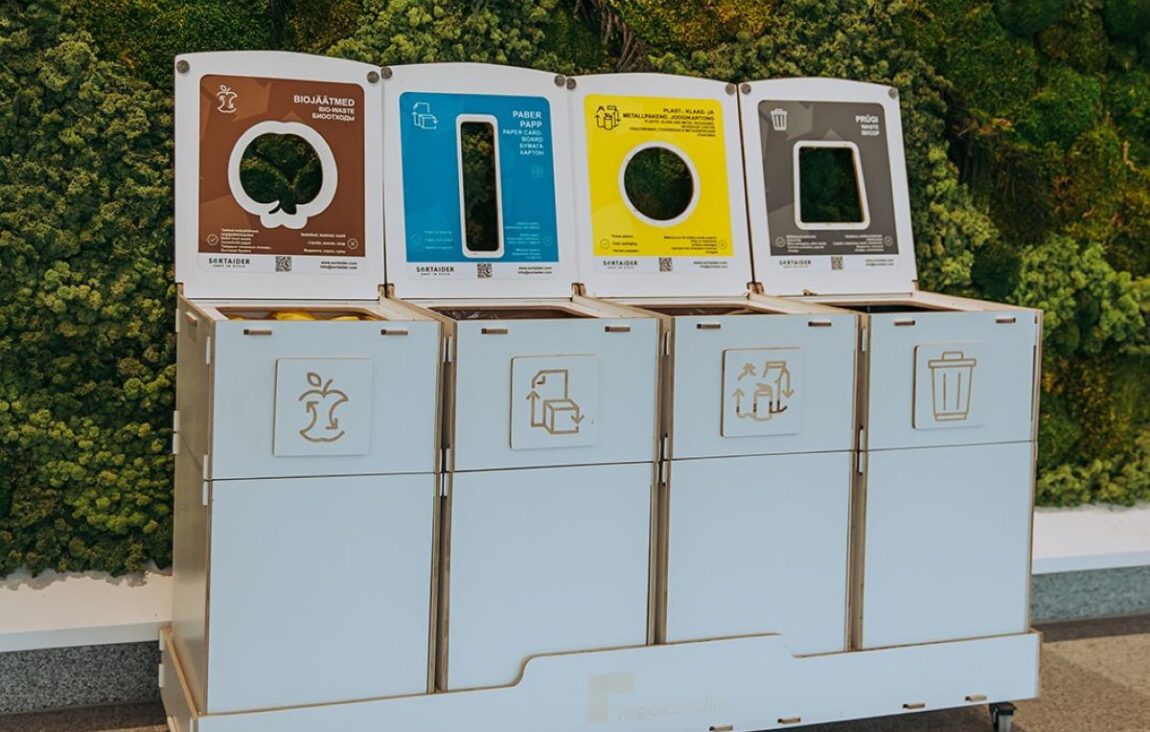 Waste bins with instructional stickers helping children understand waste sorting in a kindergarten classroom.