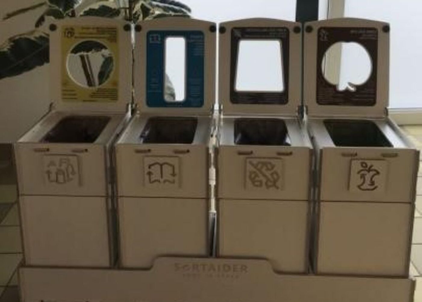 Recycling bins and four-section waste sorting stations in classrooms, designed for kids to separate bio-waste, paper, packaging, and general waste.